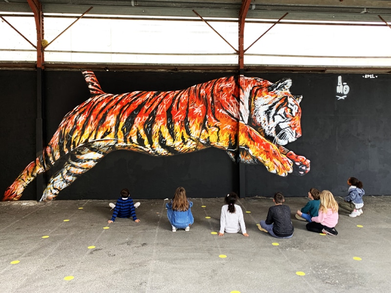 Tigre peint sur un mur par l'artiste A-MO streetart dans une école